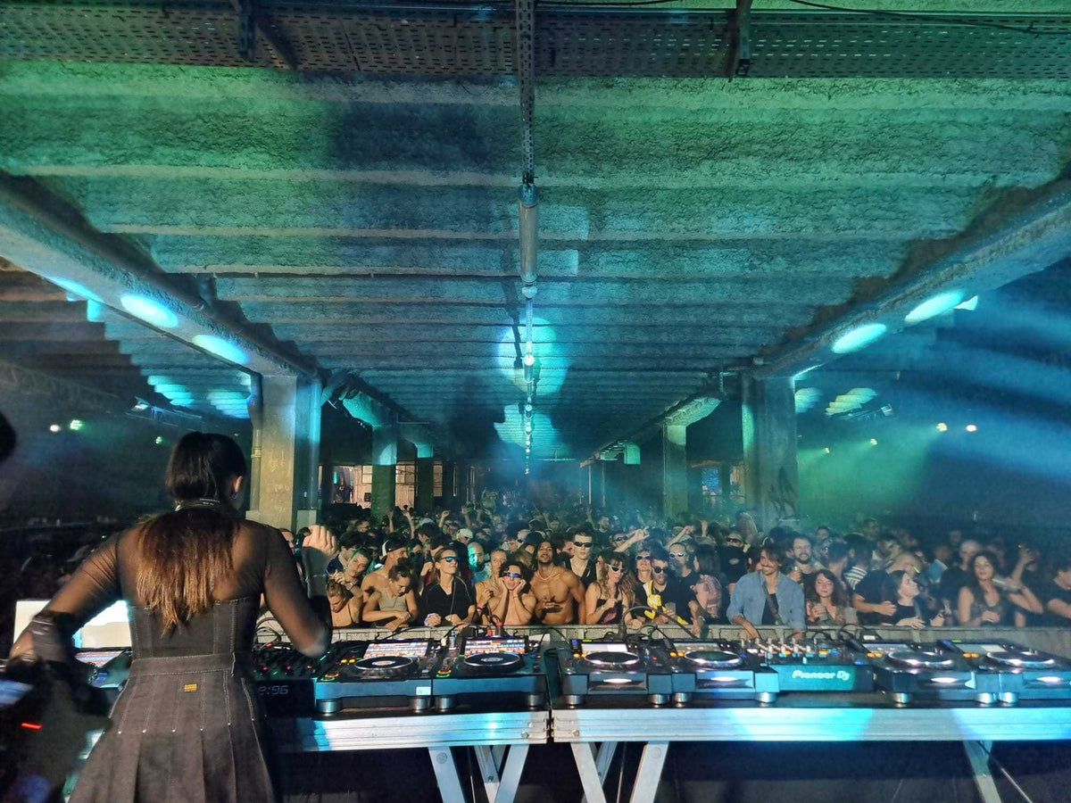 Electronic Subculture event in concrete warehouse viewed from the DJ booth